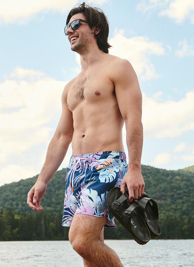 Homme qui marche sur la plage avec un short de plage bleu