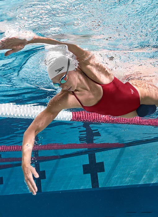 Femme qui fait de la natation dans une piscine avec un maillot de bain une pièce Speedo rouge